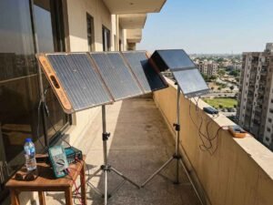 Flex Solar 60W and BigBlue 28W portable panels mounted on tripods side-by-side on an apartment balcony during a real-world voltage output test with multimeters.